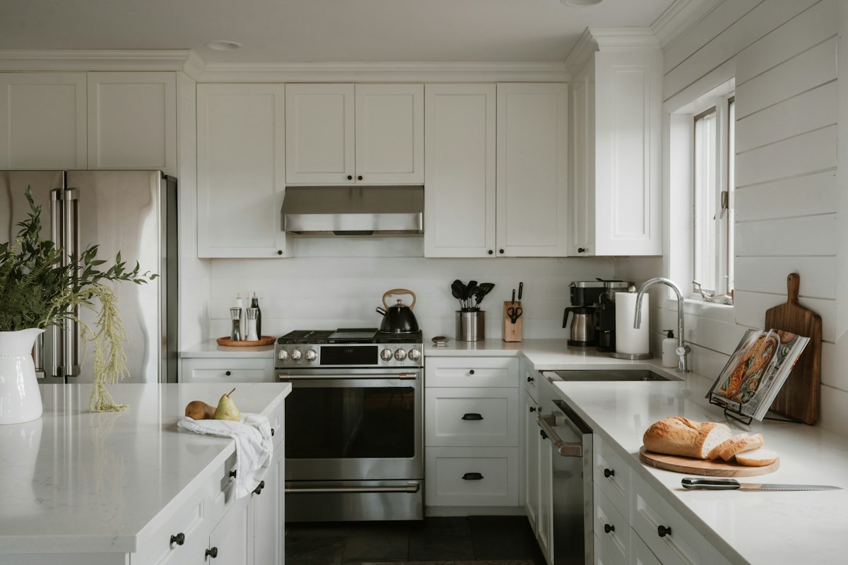 Spotless white kitchen with clean countertops and stainless appliances