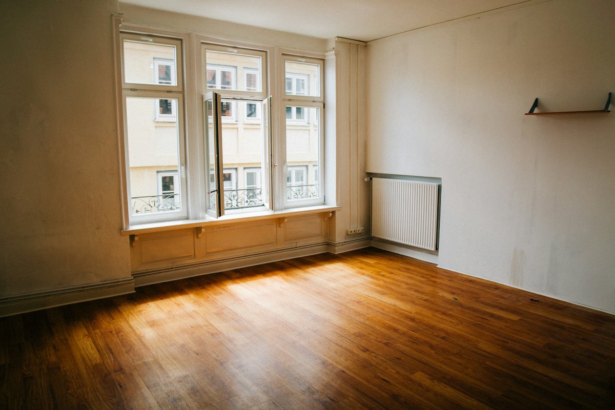 Empty, freshly cleaned room with hardwood floors ready for move-in