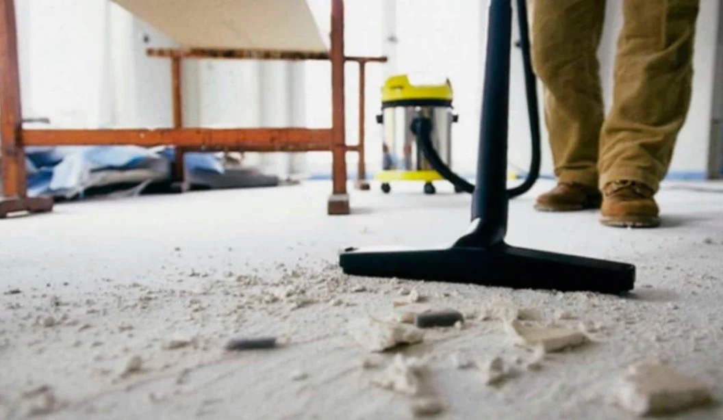 Shop vacuum clearing drywall dust and debris from a floor after construction