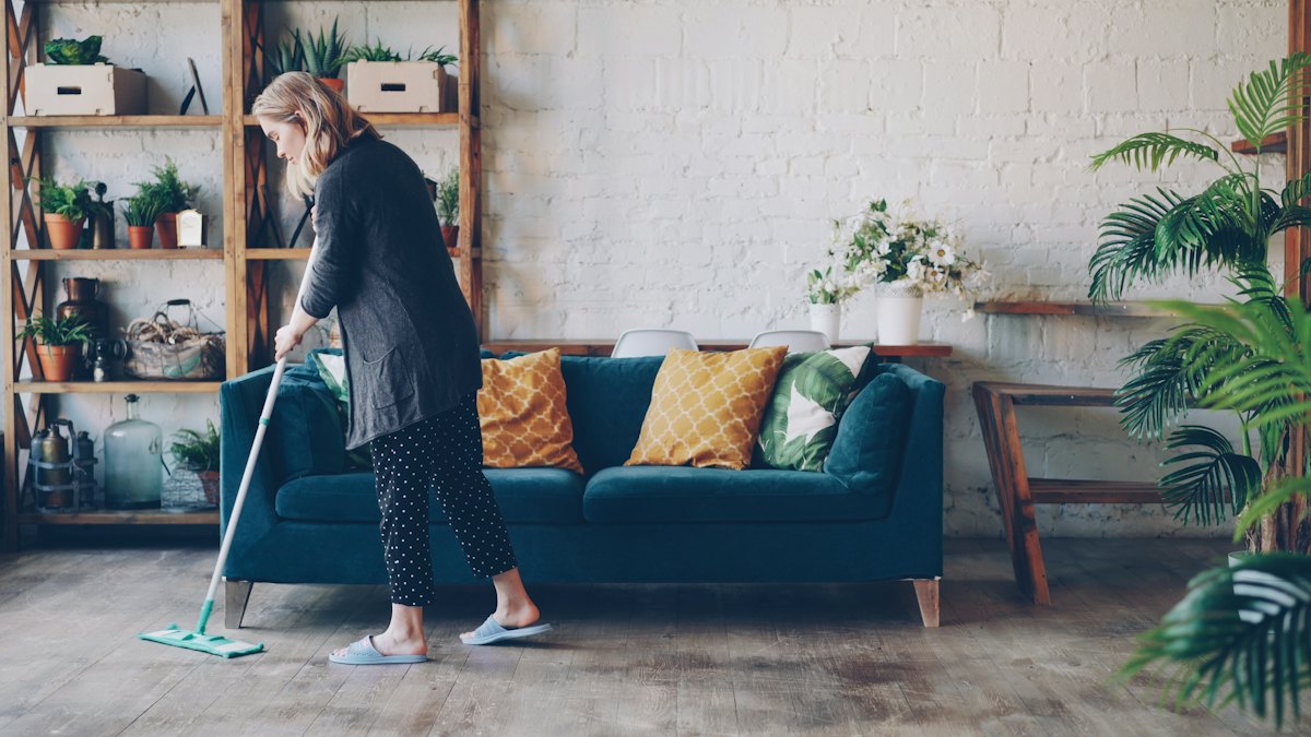House cleaner mopping the floor of a bright living room